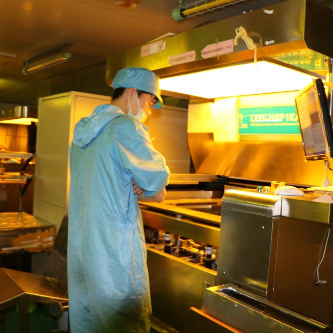 CCD exposure machine on Hongrong's bare-board line, with an operator in a cleanroom suit