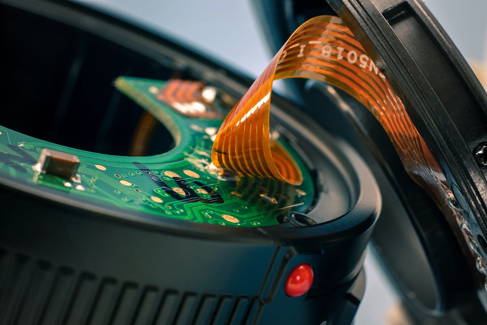 A populated green rigid board with a polyimide flexible tail looped above it